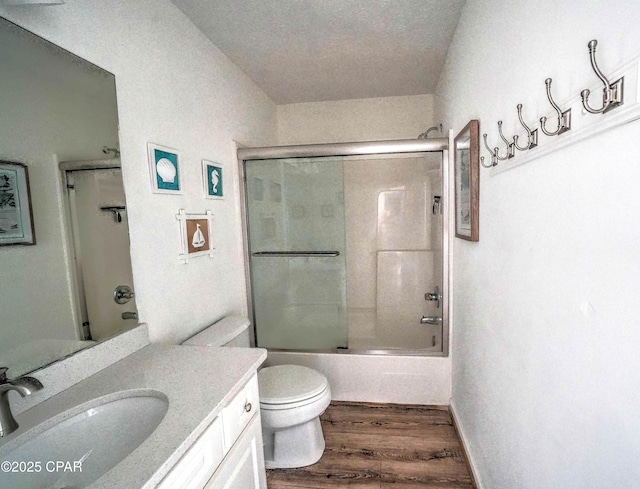 full bathroom featuring wood-type flooring, toilet, vanity, and bath / shower combo with glass door