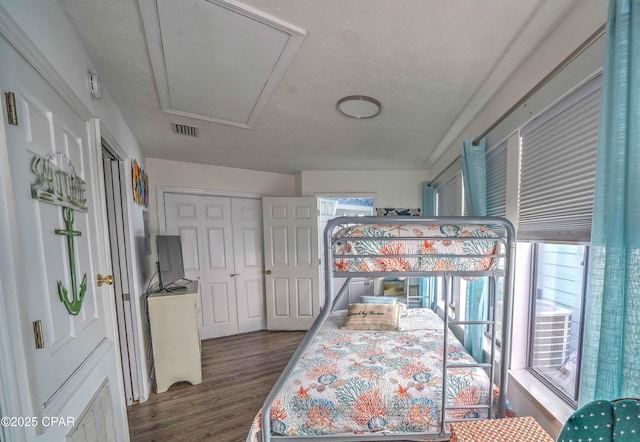 bedroom featuring multiple windows, dark wood-type flooring, and a textured ceiling