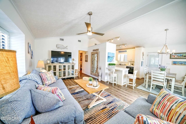 living room with vaulted ceiling, ceiling fan with notable chandelier, a textured ceiling, and light wood-type flooring