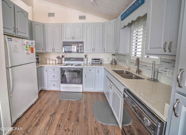 kitchen featuring sink, gray cabinetry, hardwood / wood-style floors, black appliances, and vaulted ceiling