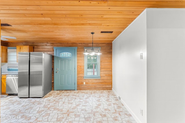 kitchen with hanging light fixtures, wood ceiling, wooden walls, and stainless steel appliances