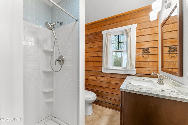 bathroom featuring a tile shower, vanity, toilet, and wood walls