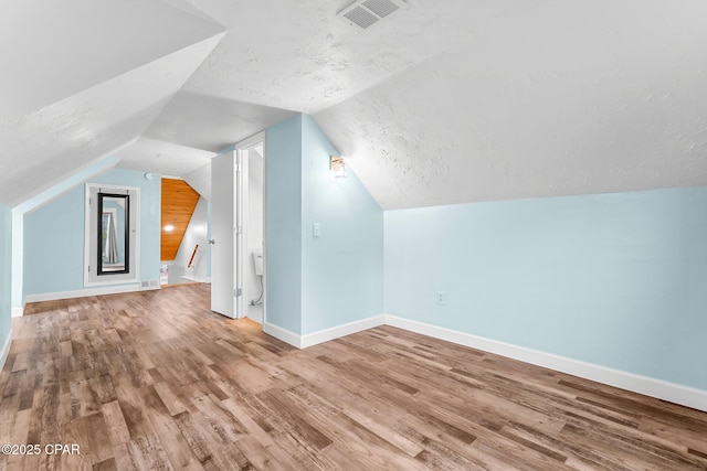 bonus room featuring vaulted ceiling, hardwood / wood-style floors, and a textured ceiling