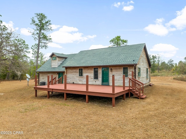 back of property with a wooden deck, a yard, and central AC