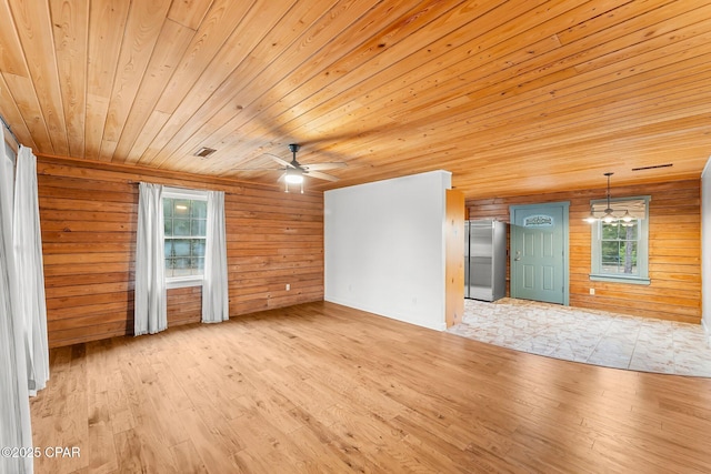 unfurnished living room with ceiling fan, wood walls, wood ceiling, and light hardwood / wood-style flooring