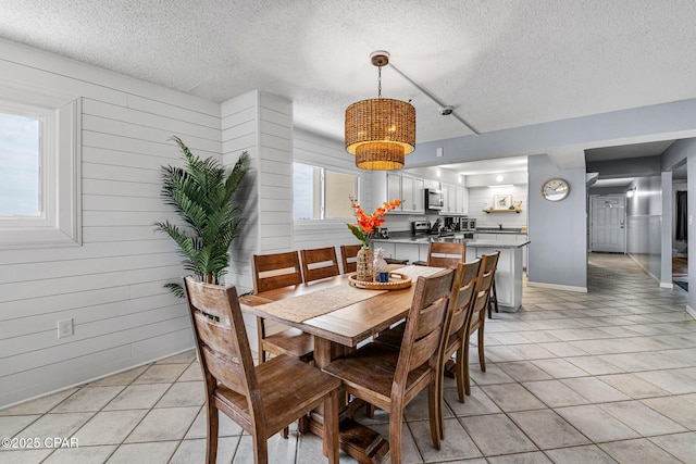 5801 Thomas Dr Unit 601, Panama City Beach, FL 32408 - dining area with a notable chandelier, a textured ceiling, wooden walls, and light tile patterned floors