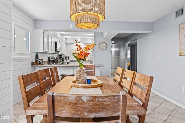 5801 Thomas Dr Unit 601, Panama City Beach, FL 32408 - dining area with a textured ceiling, light tile patterned flooring, a chandelier, baseboards, and visible vents