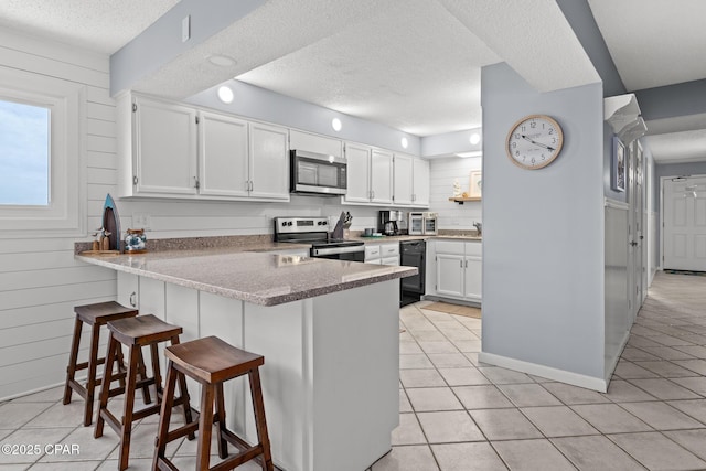 5801 Thomas Dr Unit 601, Panama City Beach, FL 32408 - kitchen featuring light tile patterned flooring, a textured ceiling, appliances with stainless steel finishes, and a peninsula