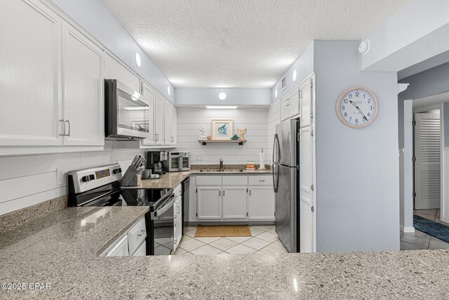 5801 Thomas Dr Unit 601, Panama City Beach, FL 32408 - kitchen with light stone counters, appliances with stainless steel finishes, a sink, and light tile patterned floors
