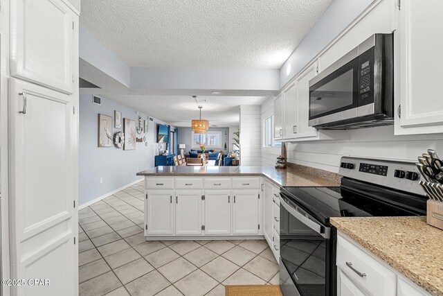 5801 Thomas Dr Unit 601, Panama City Beach, FL 32408 - kitchen featuring a textured ceiling, light tile patterned floors, white cabinets, a peninsula, and appliances with stainless steel finishes