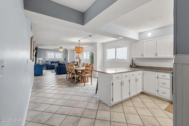 5801 Thomas Dr Unit 601, Panama City Beach, FL 32408 - kitchen featuring a peninsula, a textured ceiling, white cabinets, and open floor plan