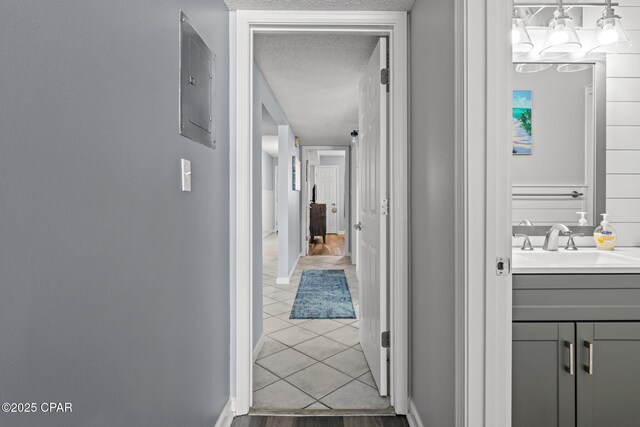 5801 Thomas Dr Unit 601, Panama City Beach, FL 32408 - hallway featuring electric panel, tile patterned floors, a sink, a textured ceiling, and baseboards