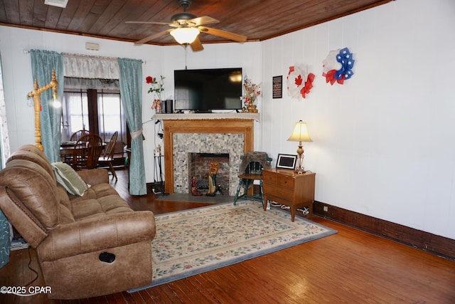 living area featuring baseboards, wooden ceiling, ceiling fan, wood finished floors, and a fireplace