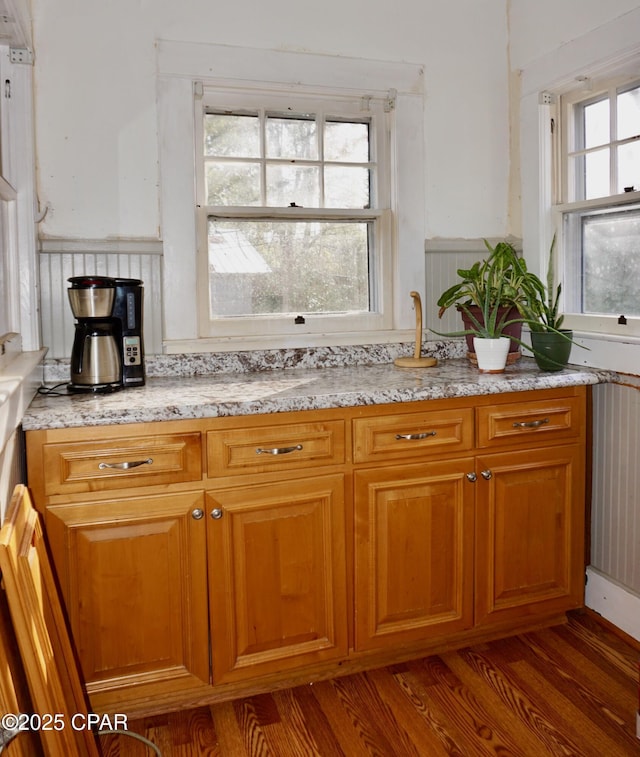 kitchen featuring a healthy amount of sunlight, dark wood finished floors, and light stone countertops