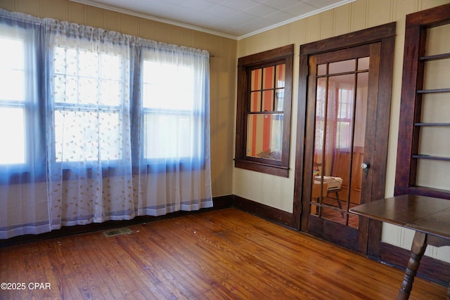 unfurnished room featuring dark wood-style floors, visible vents, ornamental molding, and baseboards