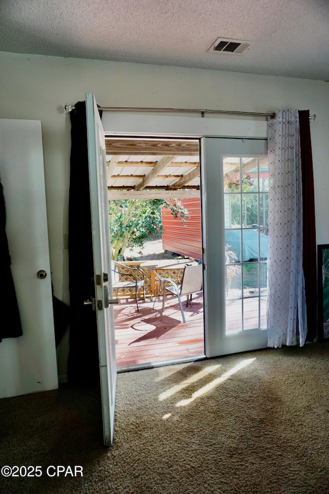 doorway featuring carpet floors, visible vents, and a textured ceiling