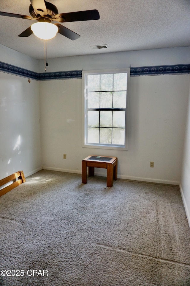 empty room featuring visible vents, carpet flooring, ceiling fan, a textured ceiling, and baseboards