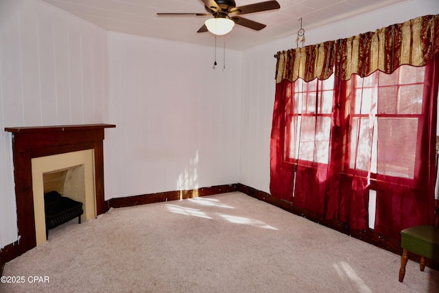 unfurnished living room featuring ceiling fan, carpet floors, a fireplace, and baseboards