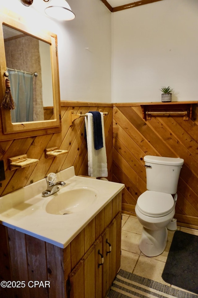 bathroom featuring wainscoting, toilet, tile patterned flooring, vanity, and wood walls