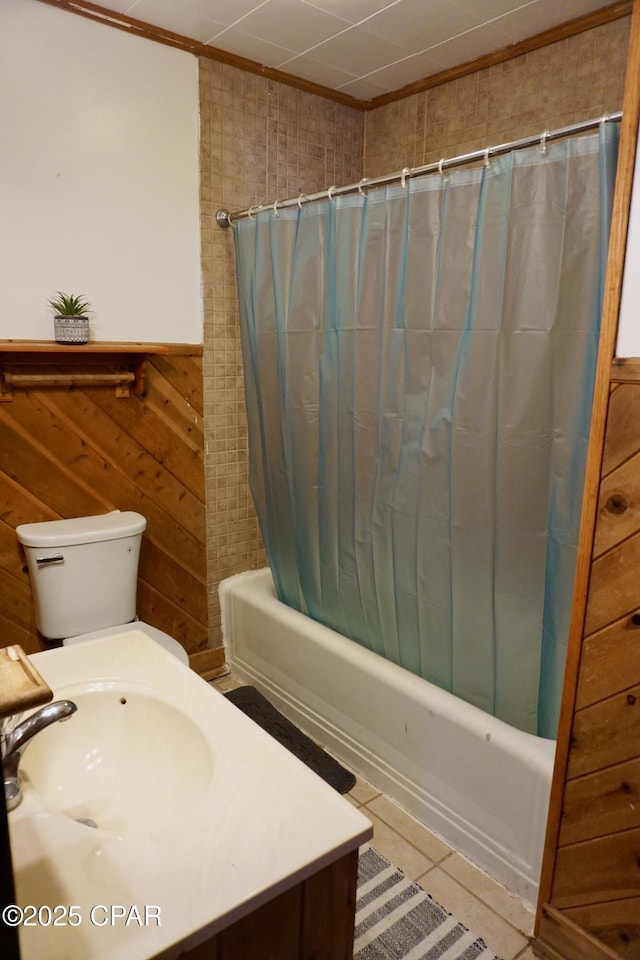 full bathroom with a wainscoted wall, tile patterned floors, shower / bathtub combination with curtain, wood walls, and a sink