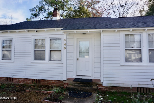 doorway to property featuring crawl space, roof with shingles, and a chimney