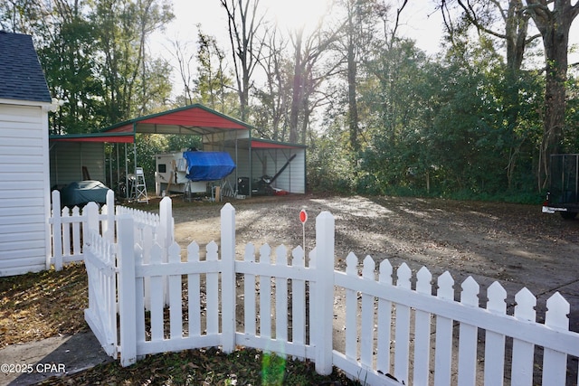 view of yard featuring driveway, a fenced front yard, and a detached carport