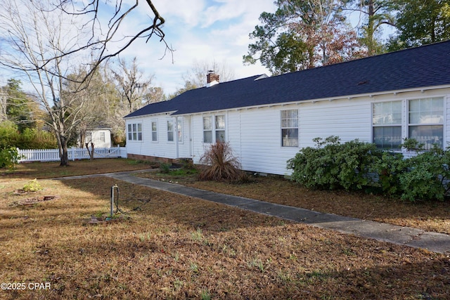 view of front of home with a shingled roof, fence, and a chimney