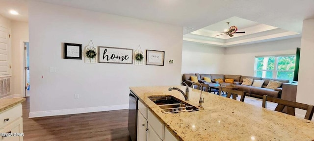 kitchen featuring sink, ceiling fan, dark hardwood / wood-style floors, light stone counters, and a raised ceiling