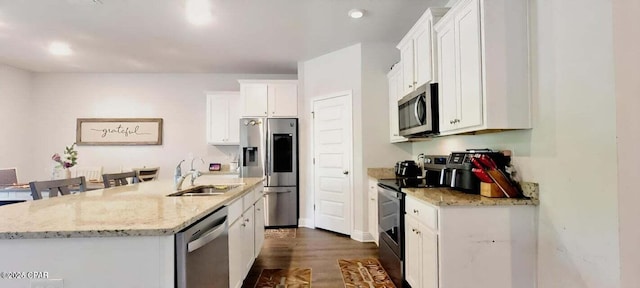 kitchen with sink, light stone counters, stainless steel appliances, a kitchen island with sink, and white cabinets