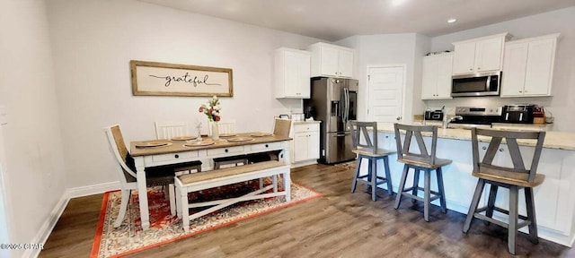 kitchen featuring appliances with stainless steel finishes, a kitchen bar, white cabinets, and light stone counters