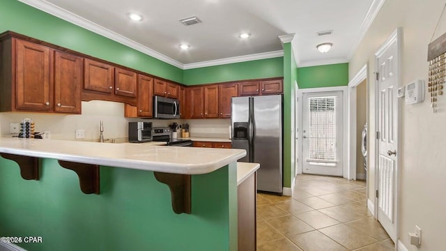 kitchen featuring a breakfast bar, visible vents, appliances with stainless steel finishes, ornamental molding, and a peninsula