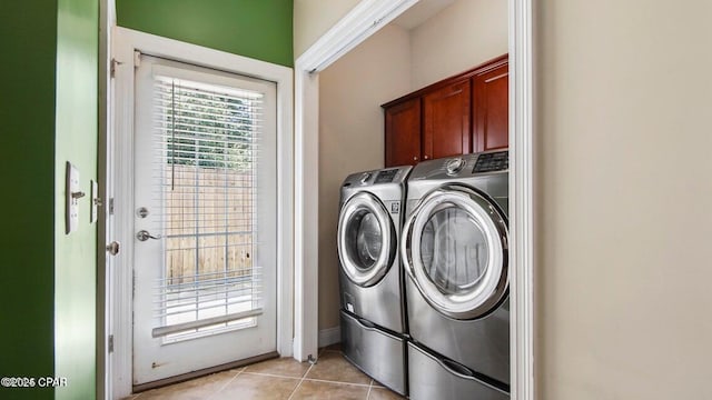 laundry area featuring washer and dryer, cabinet space, and light tile patterned flooring