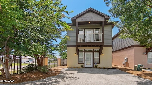 view of front of home featuring fence, a balcony, and stucco siding