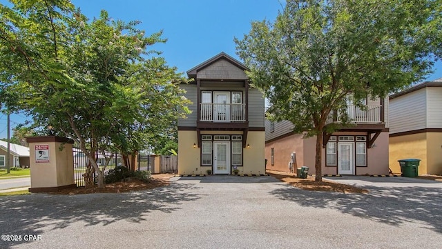 view of front of property with french doors, fence, a balcony, and stucco siding