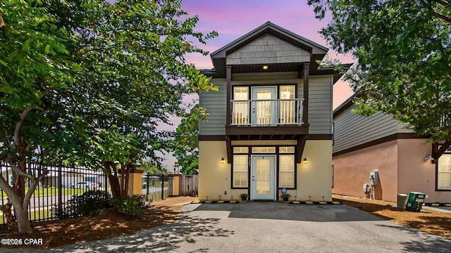 view of front of home featuring fence, a balcony, and stucco siding