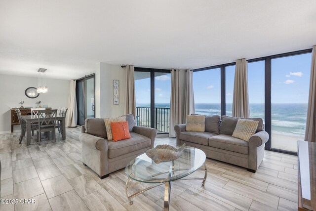 living room featuring a notable chandelier, expansive windows, and a water view