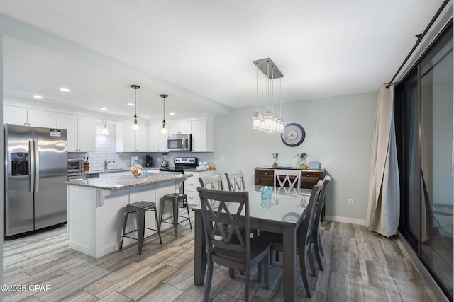 dining space with recessed lighting, wood tiled floor, baseboards, a toaster, and a notable chandelier