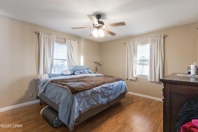 bedroom with multiple windows, wood-type flooring, and ceiling fan