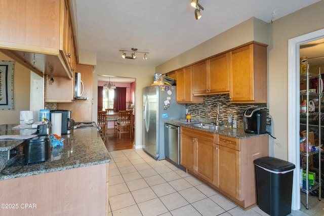 kitchen with light tile patterned flooring, sink, tasteful backsplash, dark stone counters, and stainless steel appliances