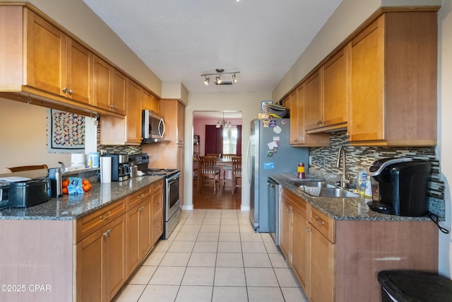 kitchen with light tile patterned flooring, appliances with stainless steel finishes, tasteful backsplash, sink, and dark stone counters