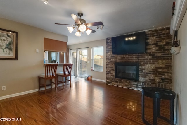 living room featuring a brick fireplace, hardwood / wood-style floors, and ceiling fan