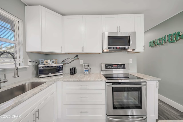 kitchen featuring sink, stainless steel appliances, light stone countertops, hardwood / wood-style floors, and white cabinets