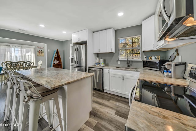 kitchen featuring white cabinetry, sink, light stone countertops, and appliances with stainless steel finishes