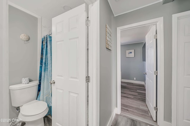 bathroom with wood-type flooring, curtained shower, crown molding, and toilet