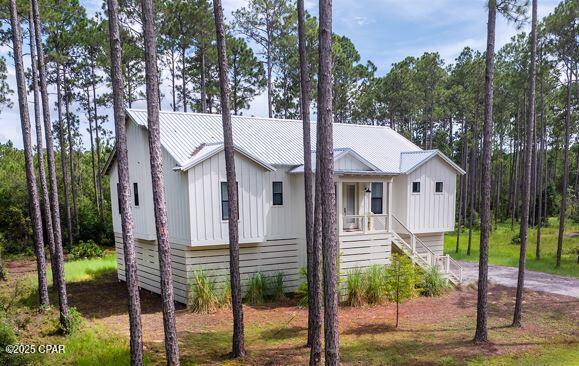 view of front of house with covered porch, board and batten siding, metal roof, and stairs