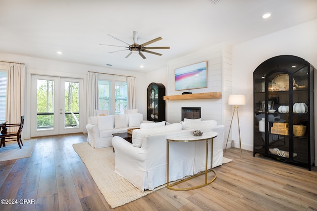 living area with a glass covered fireplace, recessed lighting, and wood-type flooring