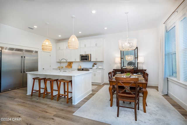 kitchen featuring visible vents, a sink, white cabinetry, stainless steel appliances, and light wood-style floors