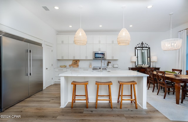 kitchen featuring a center island with sink, visible vents, light wood-style flooring, white cabinets, and appliances with stainless steel finishes