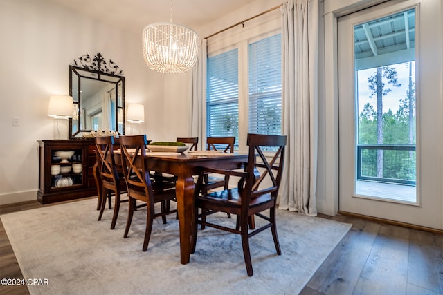 dining space featuring baseboards, an inviting chandelier, and hardwood / wood-style flooring