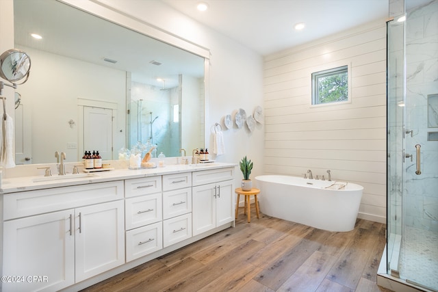 bathroom with double vanity, wood finished floors, a stall shower, and a sink